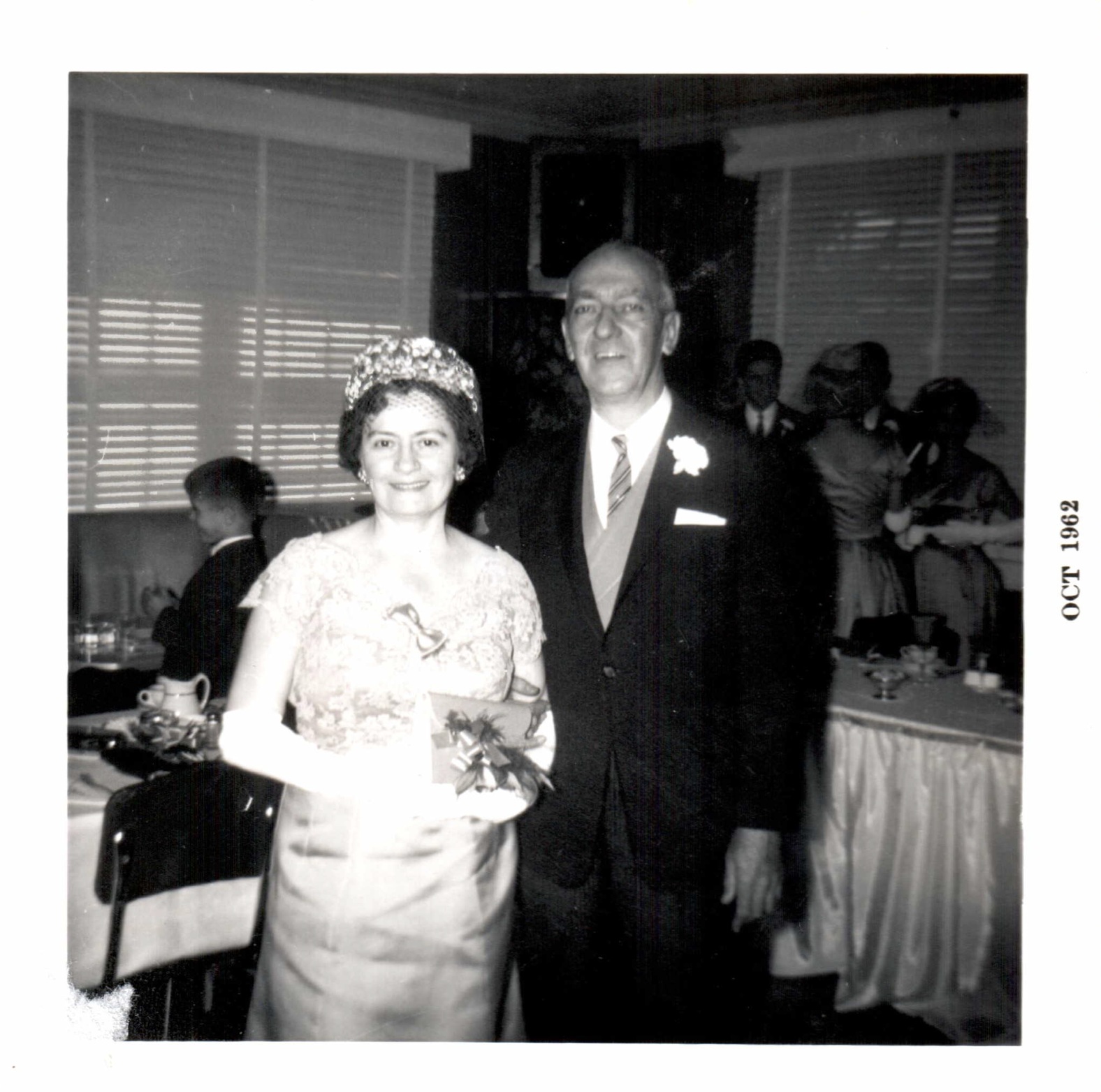 Josephine and Carl Peduzzi posing at an indoor gathering; the print border is marked October 1962