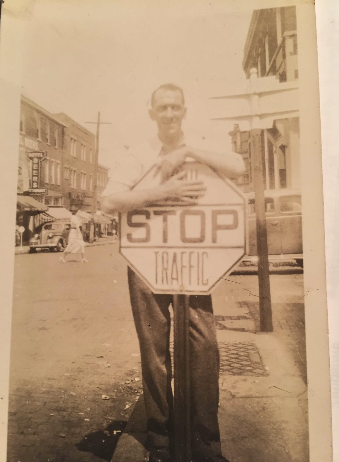 Carl Joseph Peduzzi holding a STOP traffic sign with a Hotel Beers sign in the background