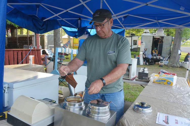 Veteran Creation Festival vendor Randy Carper preparing frozen cheesecake beneath a blue canopy in 2022