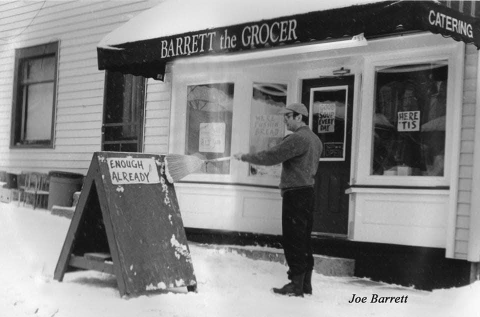 Joe Barrett standing in the snow outside Barrett the Grocer beneath the store awning