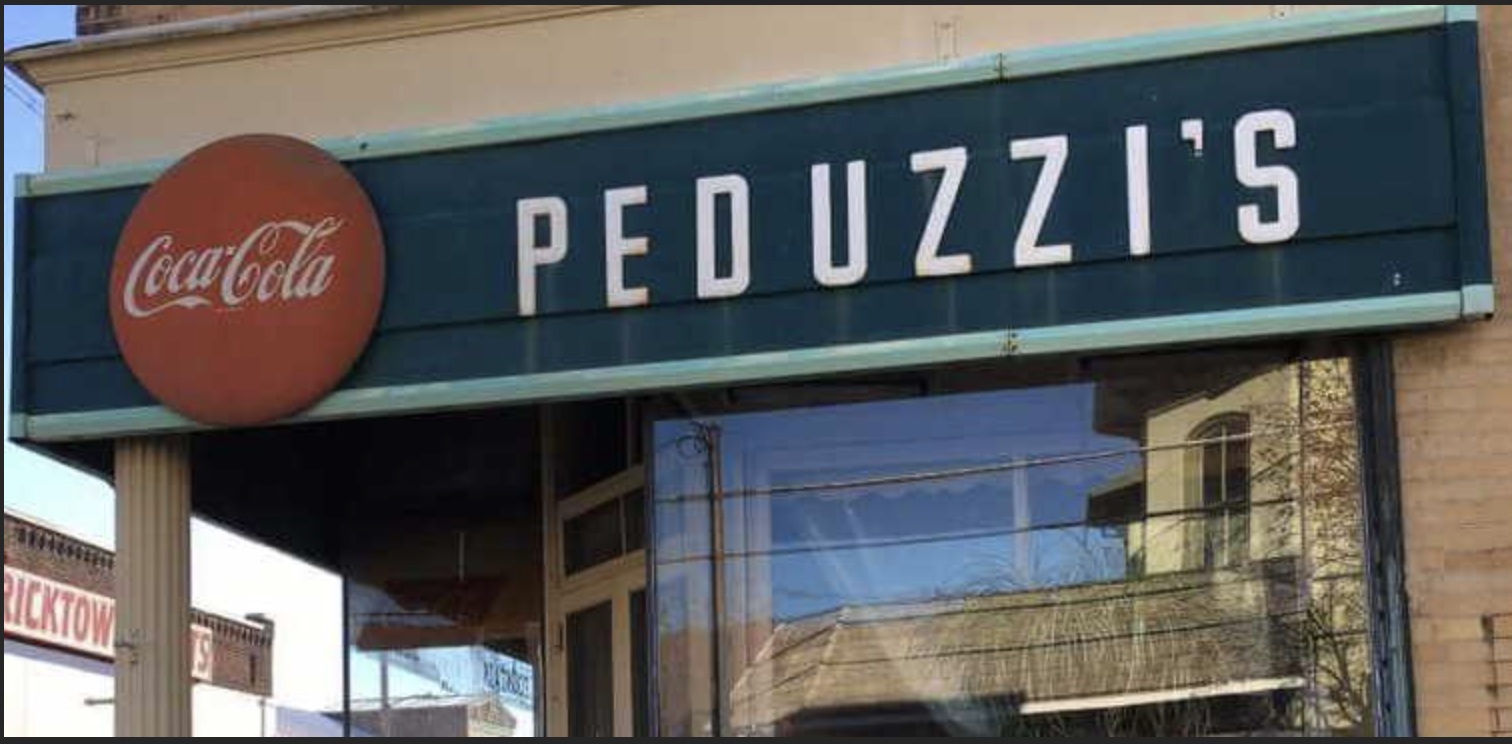 Peduzzi’s storefront name sign with a circular red Coca-Cola emblem