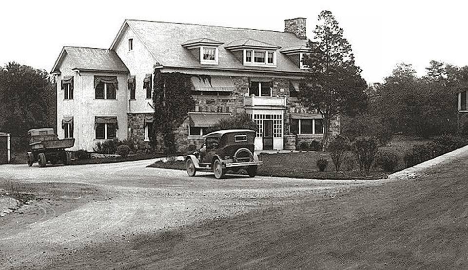 Historic black-and-white view of the Stone House before its American Legion era, with early automobiles parked outside
