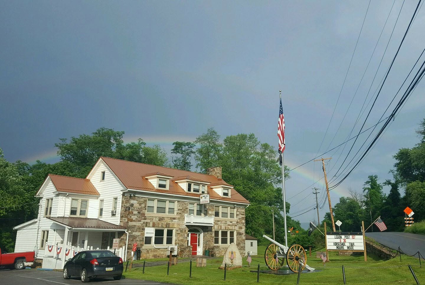 The Stone House in use as Simpson-Hunt American Legion Post 107, with flags, memorial cannon and Post 107 sign