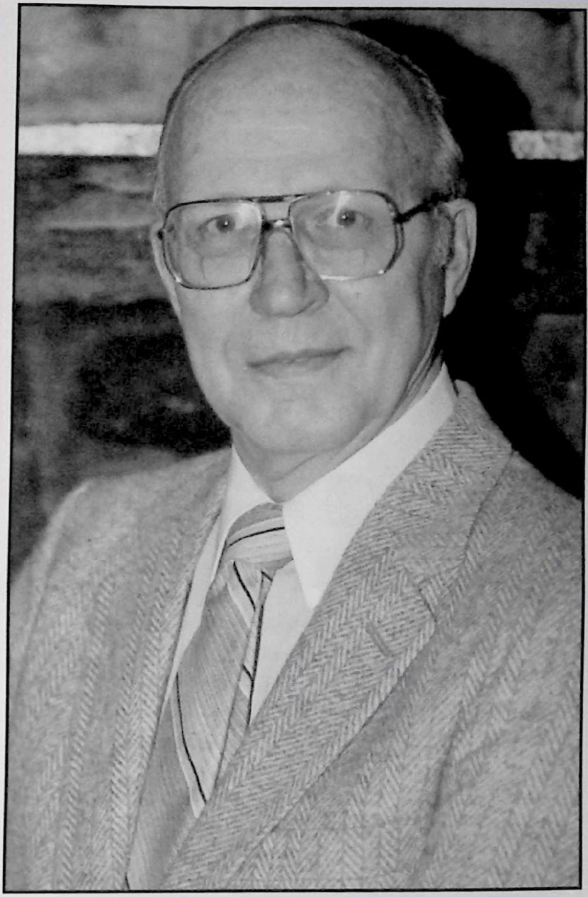 Black-and-white portrait of Robert C. &ldquo;Bob&rdquo; Goodman wearing glasses and a suit